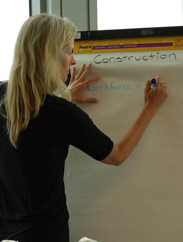 A person is writing on a flip chart with the word 