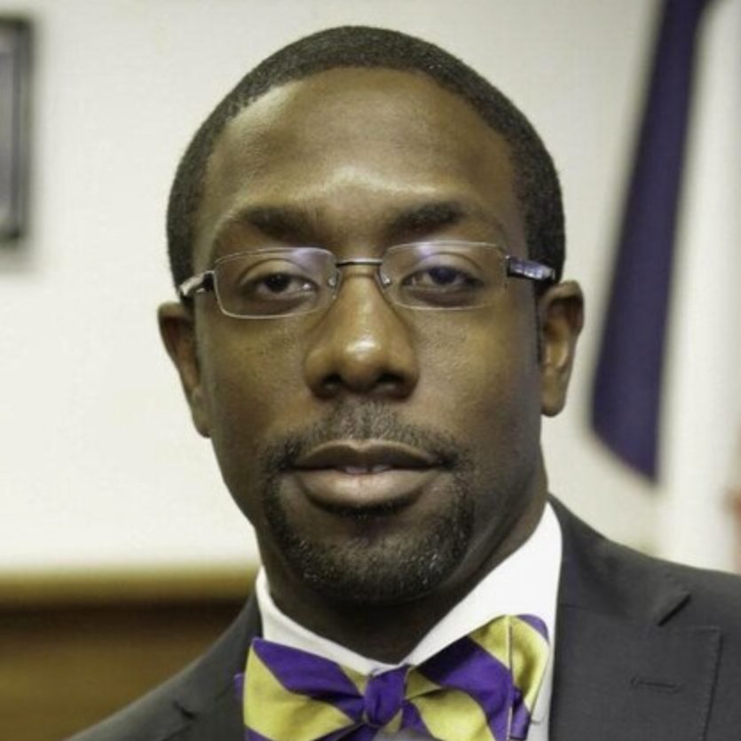 A person poses for a portrait wearing glasses and a bow tie.