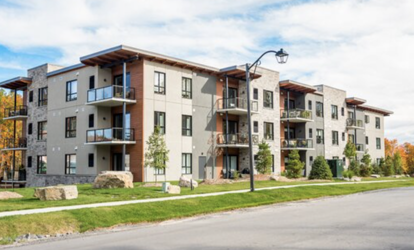 A modern multi-family residential building with balconies and a street lamp in the foreground.