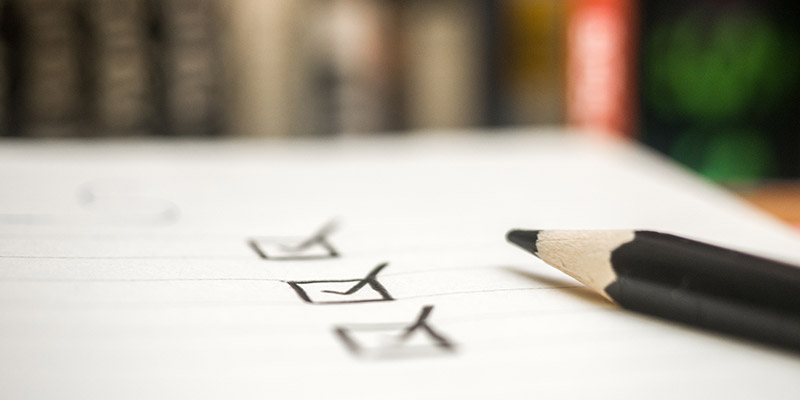 A pencil lies next to a checklist with several items marked off, symbolizing task completion or organization.